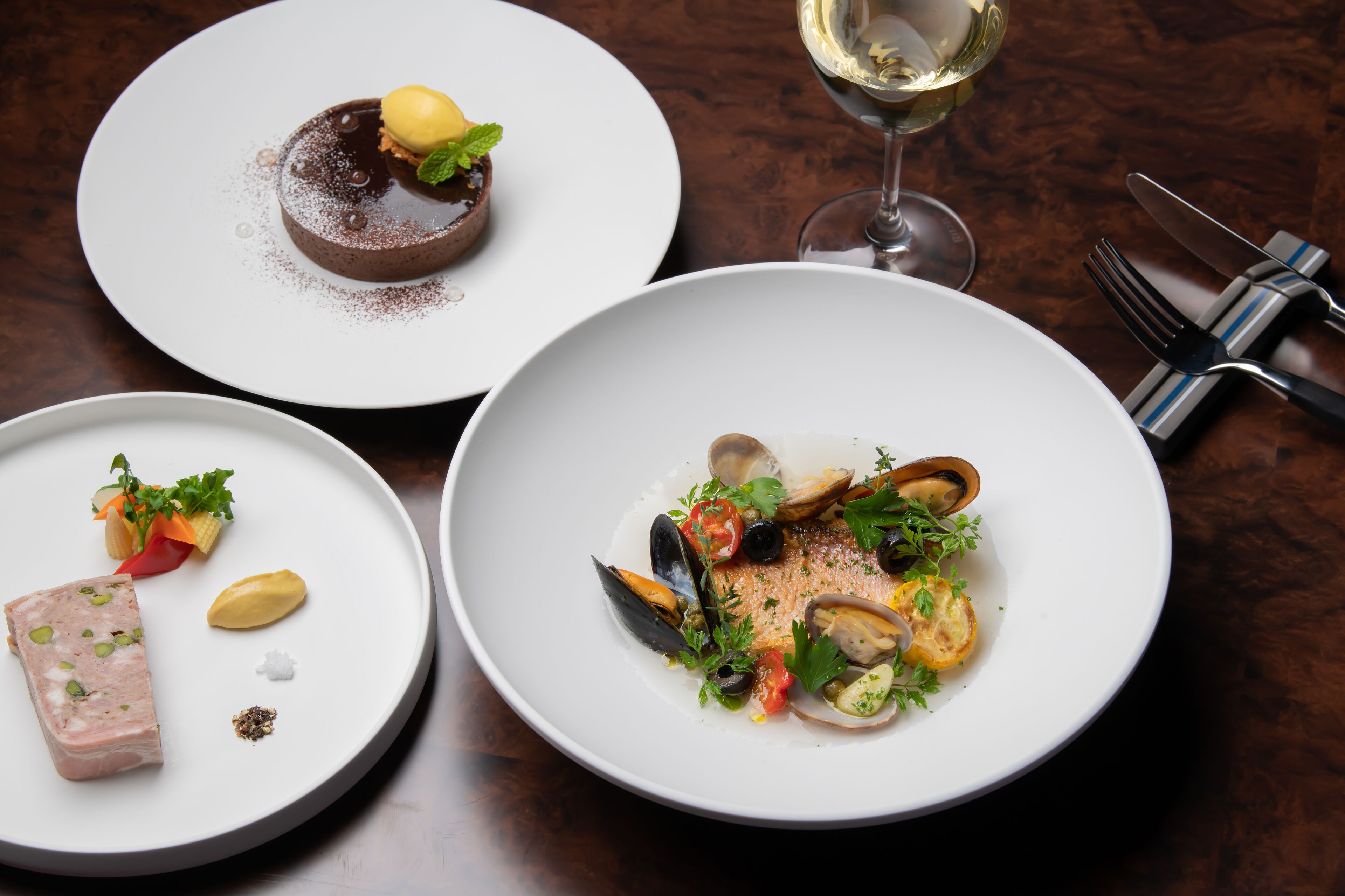 Three plates of food on a wooden table.
