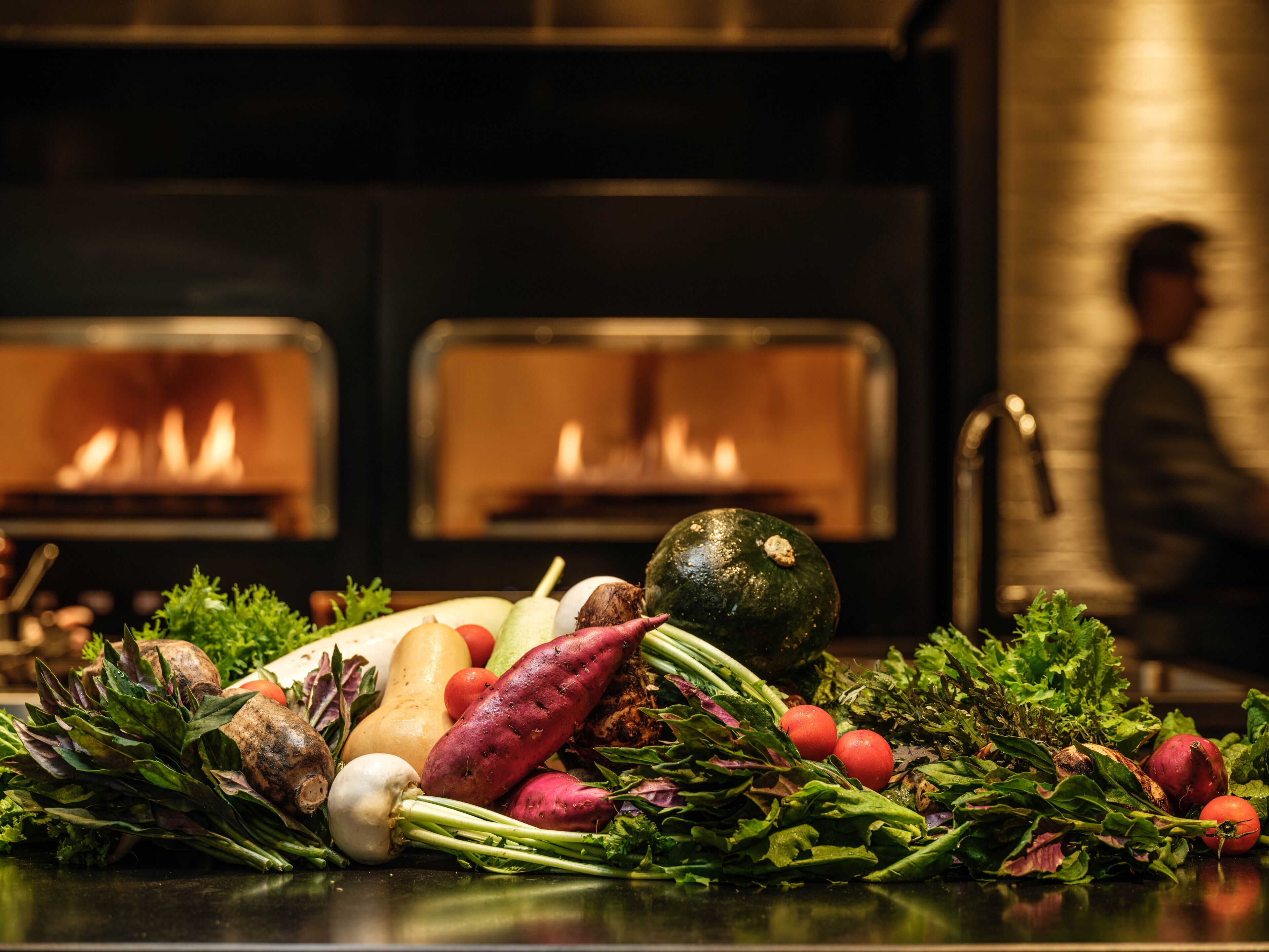 Variedad de verduras frescas frente a una cocina con dos hornos.