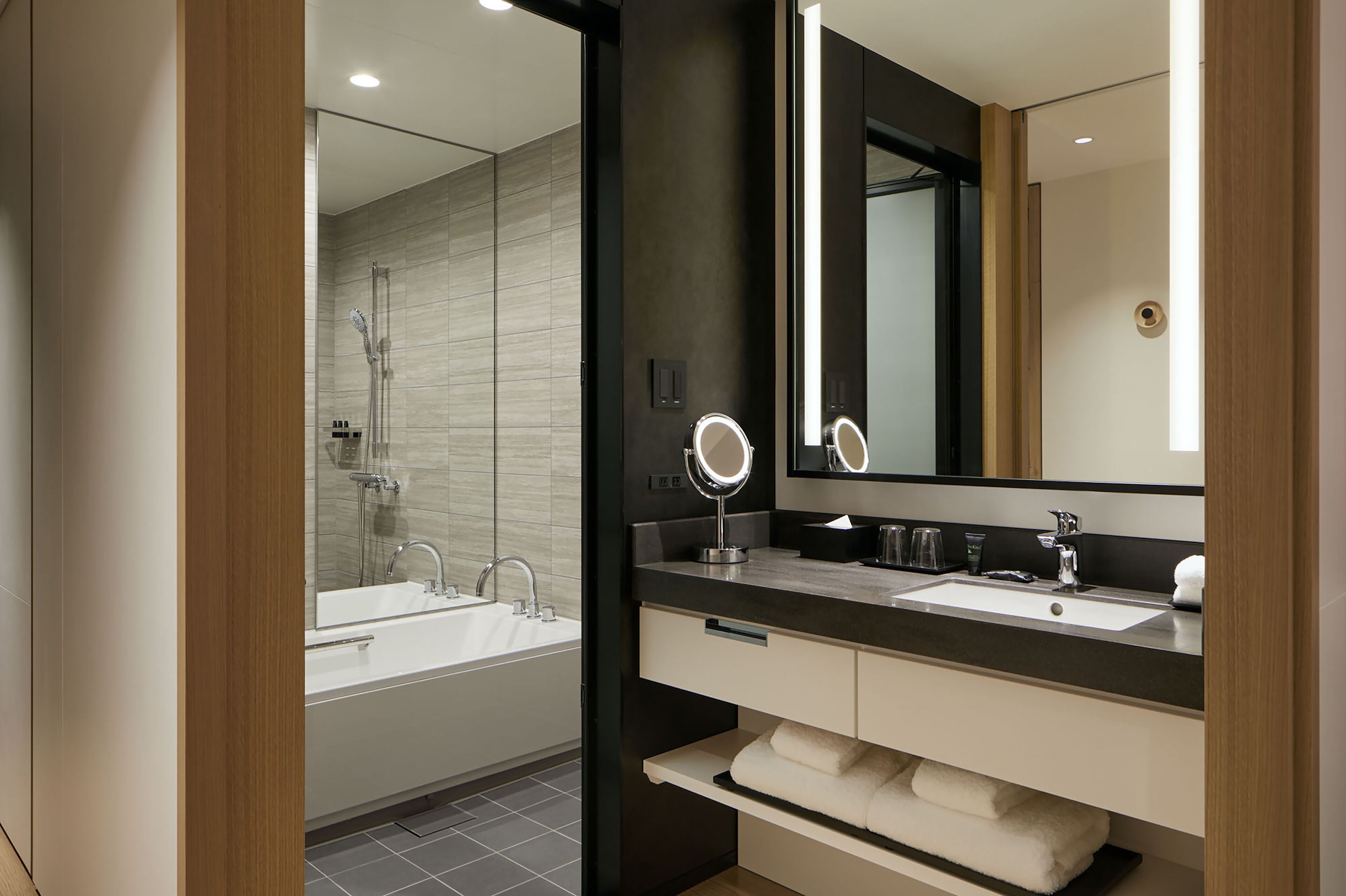 Une salle de bain moderne avec un grand miroir, deux lavabos et une douche.