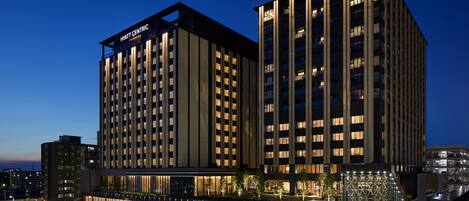 Un hotel moderno con un llamativo letrero de 'Hyatt Centric', fachada de vidrio y un letrero de 'Cross Gate Kanazawa' debajo.