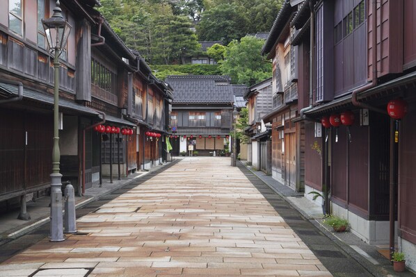 A traditional Japanese street with wooden buildings, a paved walkway, and red lanterns.