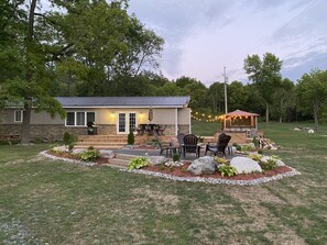 Una casa con un patio amueblado al aire libre, una parrilla y un cobertizo pequeño.