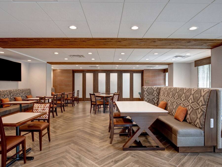 A restaurant with wooden flooring, booths, and tables.