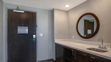 Une salle de bain avec une porte en bois, un lavabo blanc et un miroir.