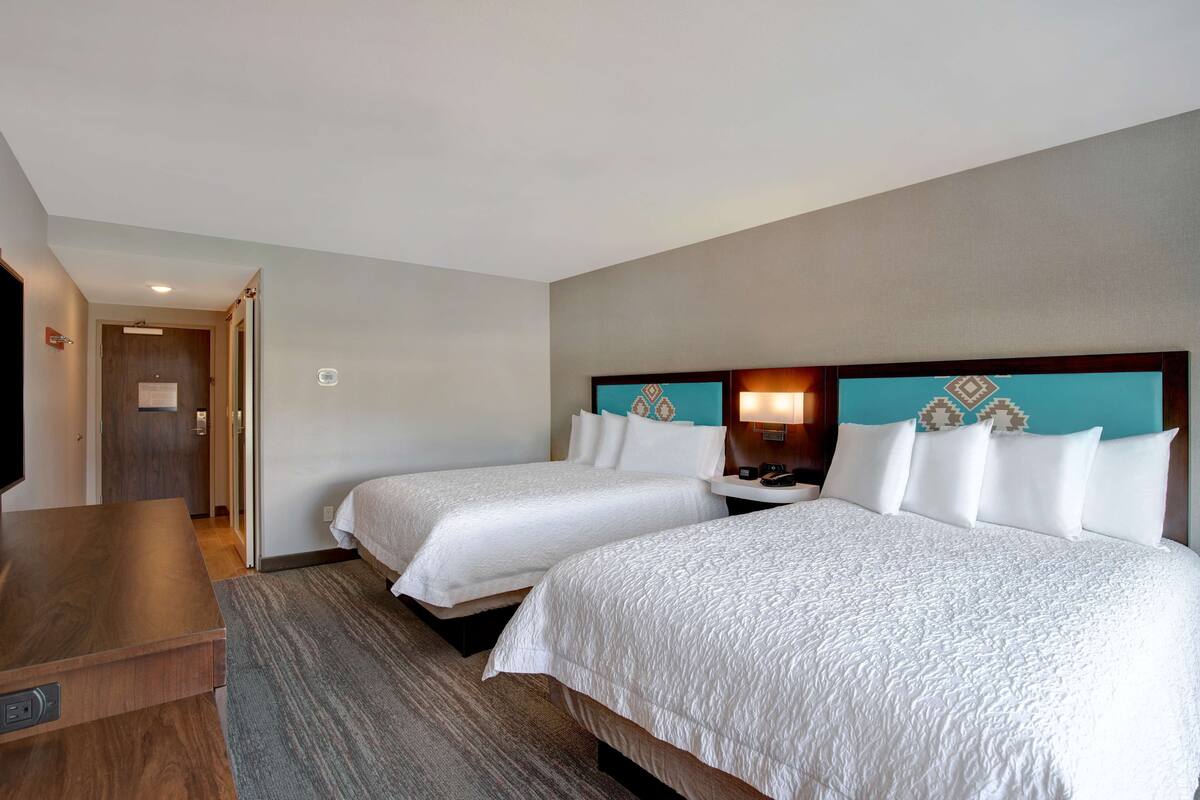 Une chambre d’hôtel avec deux lits, un bureau en bois et un téléviseur.