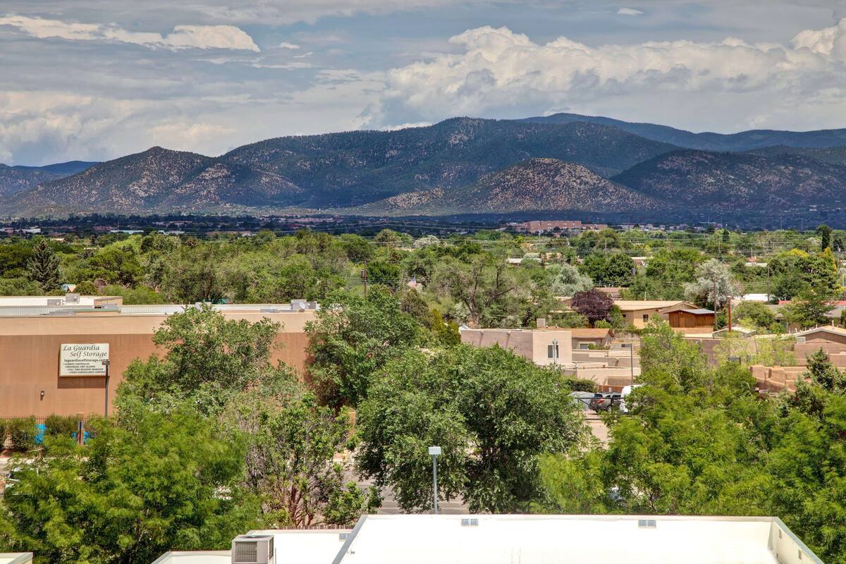 Une ville avec des montagnes en arrière-plan, des bâtiments avec des enseignes et des arbres au premier plan.