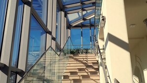 A modern staircase with glass railings and a clear view of the sky through the upper glass panels. - Kasztanowy Pałac (Tarnowo Podgorne)