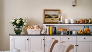 A kitchen with white cabinets, a dining table with chairs, and a variety of food items and kitchenware on the counter. - Kasztanowy Pałac (Tarnowo Podgorne)