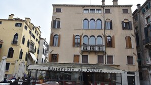 A restaurant with outdoor seating, a tiled pavement, and classic architecture.