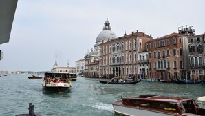 A canal with boats, historic buildings, and a prominent dome structure.