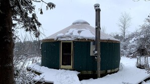 Lumipeitteinen jurtta, jossa on yksi ovi ja savupiippu.