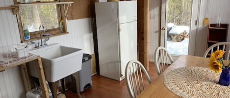 A compact kitchen with a sink, refrigerator, and wooden dining table.