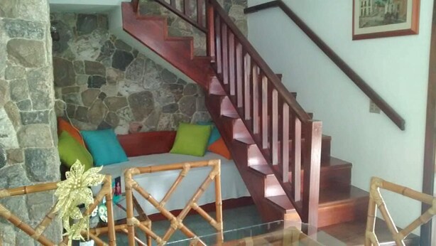 A staircase with wooden railings leading to a stone wall. - House for rent in the Center of Ubatuba (Ubatuba)