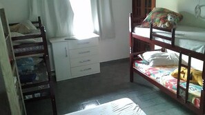 Une chambre de dortoir avec des lits superposés, un bureau et une fenêtre avec des rideaux.
