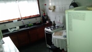 A kitchen with a gas stove, sink, and a refrigerator. - House for rent in the Center of Ubatuba (Ubatuba)