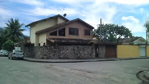 A two-story house with a stone wall and a yellow door. - House for rent in the Center of Ubatuba (Ubatuba)