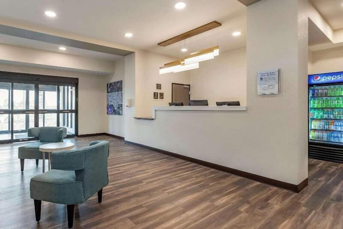 A reception area with a counter, seating, a refrigerator with beverages, and a large window.