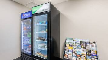 A vending machine with Pepsi and a freezer, and a display of travel brochures.