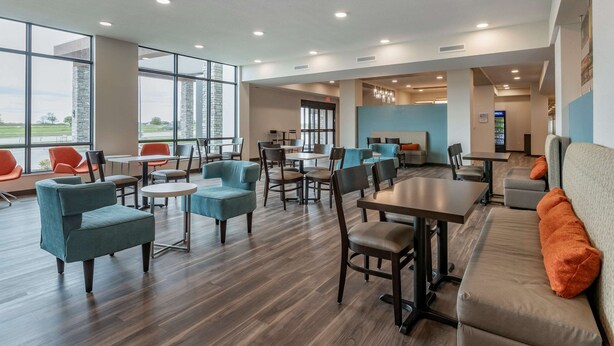 A modern hotel lobby with large windows, multiple seating areas, and a reception desk. - MainStay Suites Waukee - West Des Moines (Waukee)