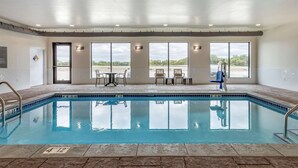 An indoor swimming pool with clear glass walls, a tiled floor, and a view of the outdoors. - MainStay Suites Waukee - West Des Moines (Waukee)