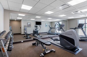 Un gimnasio con diverso equipo de ejercicio, incluyendo cintas de correr, una bicicleta estática y máquinas de pesas.