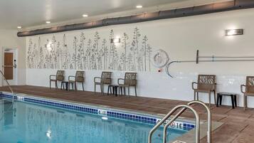 Una piscina interior con carriles claramente delimitados, una silla de socorrista y una pared con un mural floral.
