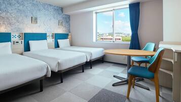 Hotellihuone, jossa on kaksi erillistä sänkyä, pieni pyöreä pöytä, tuoli ja ikkuna, josta on näkymä rakennuksiin.