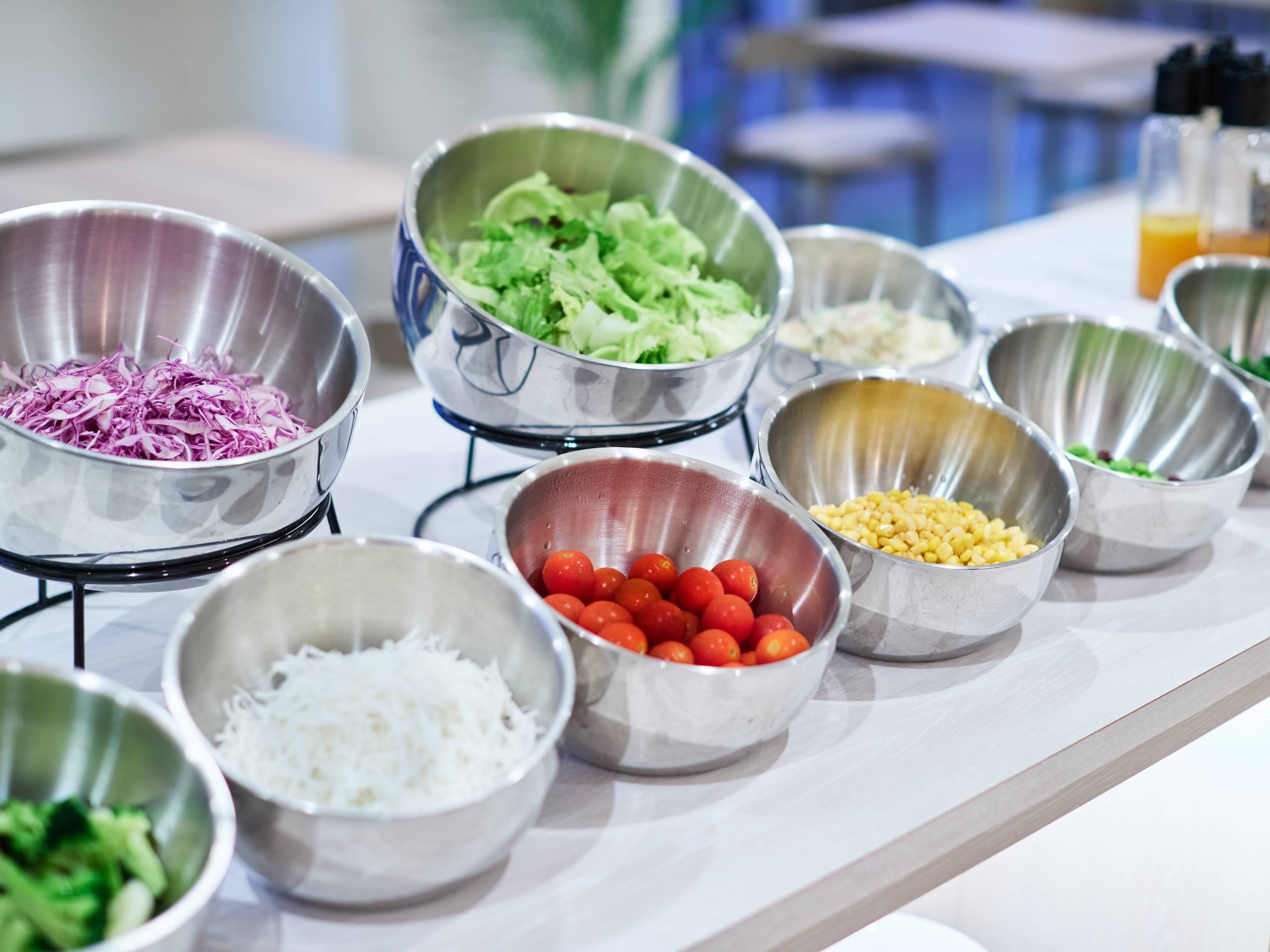 A buffet table with various food items in metal bowls.