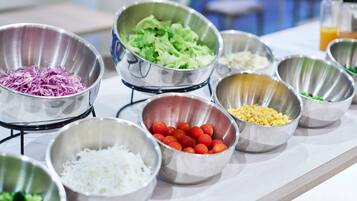 A buffet table with various food items in metal bowls.