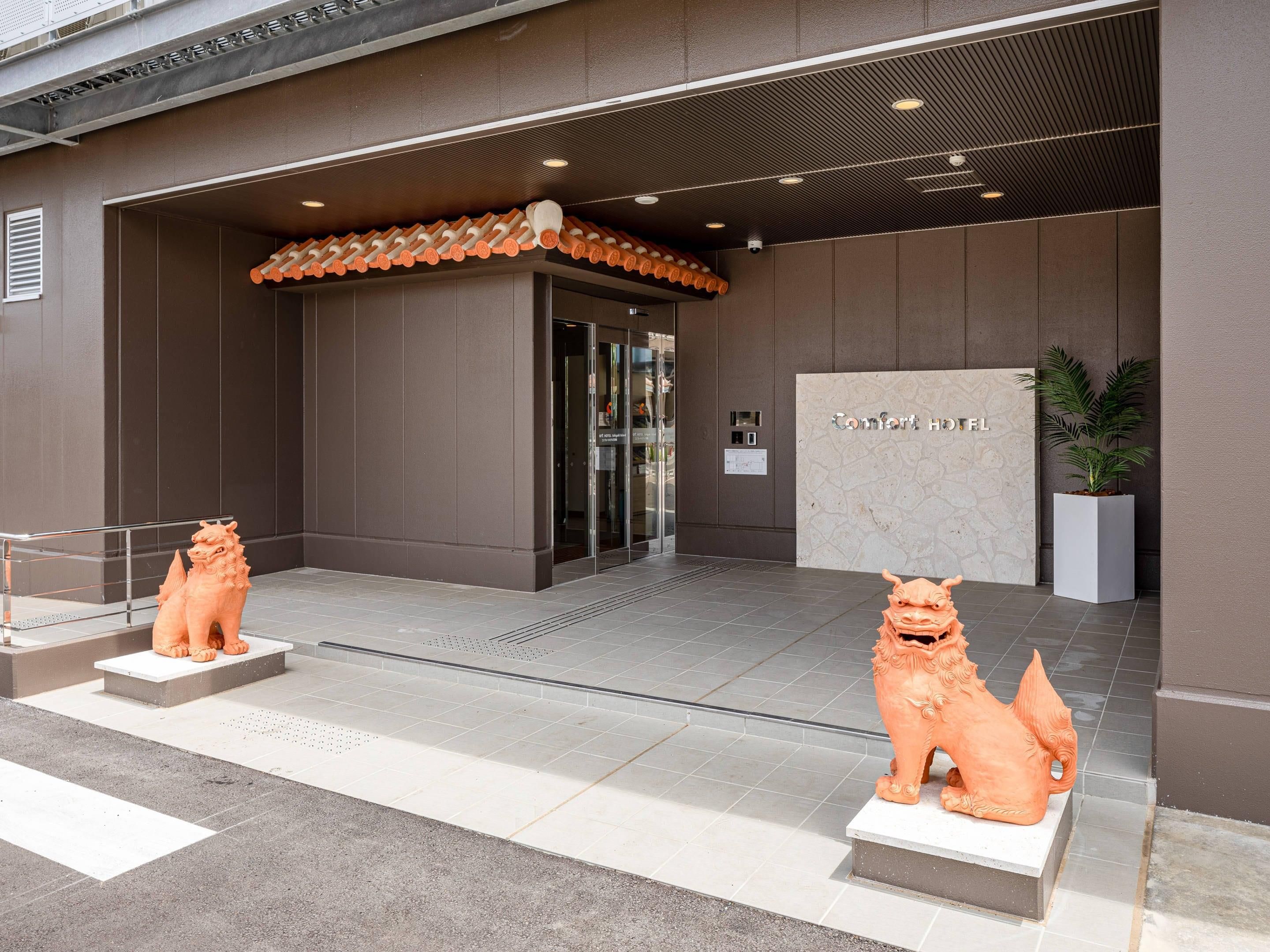 A hotel entrance with a modern design, a reception desk, and two lion statues.