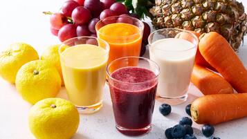 A variety of fresh fruits and vegetables, including lemons, grapes, pineapple, carrots, and blueberries, arranged on a surface.
