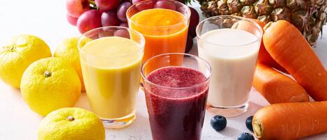 A variety of fresh fruits and vegetables, including lemons, grapes, pineapple, carrots, and blueberries, arranged on a surface.