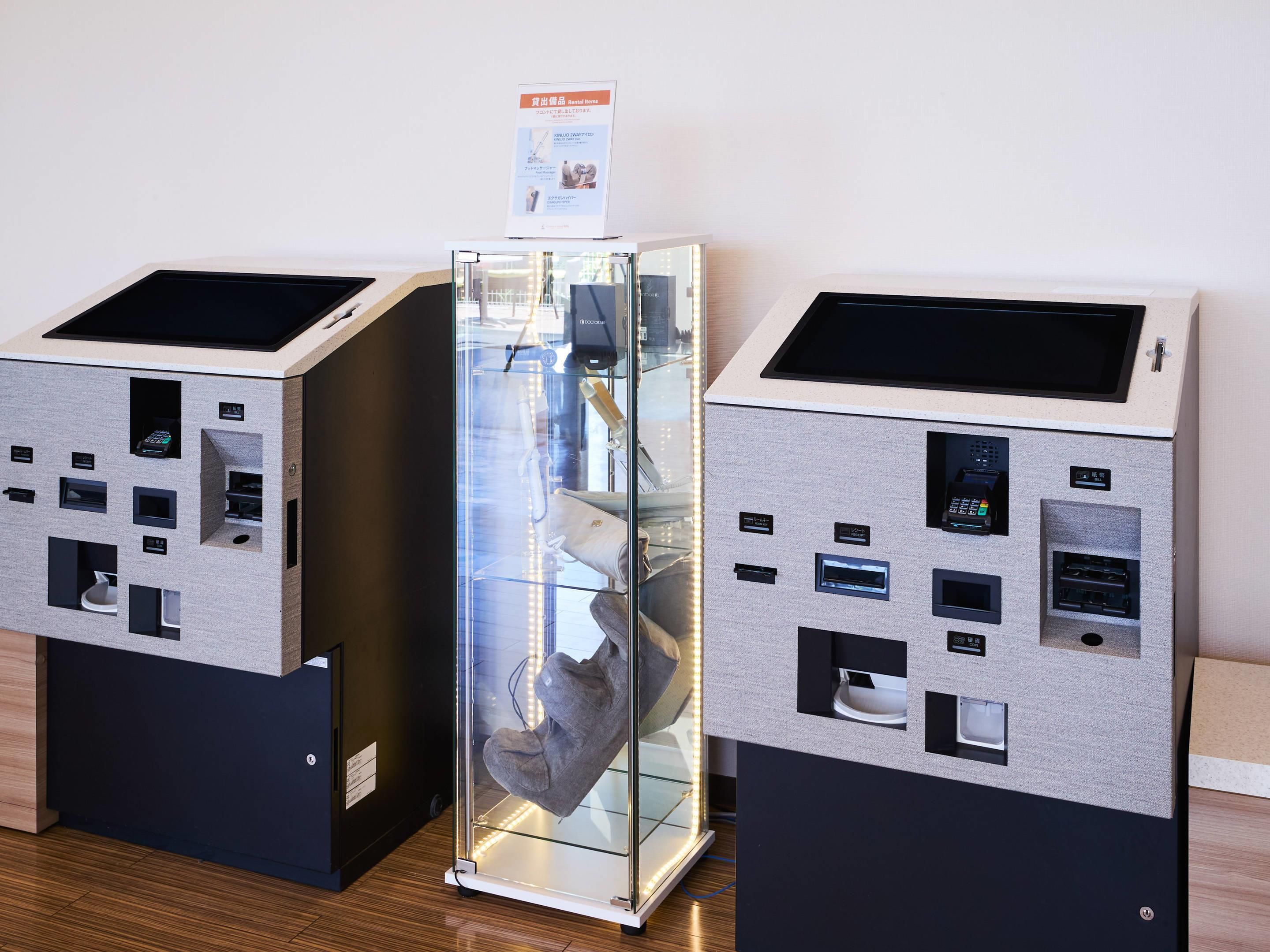 Two self-service kiosks with card payment options, a glass display case, and a sign indicating rental items.