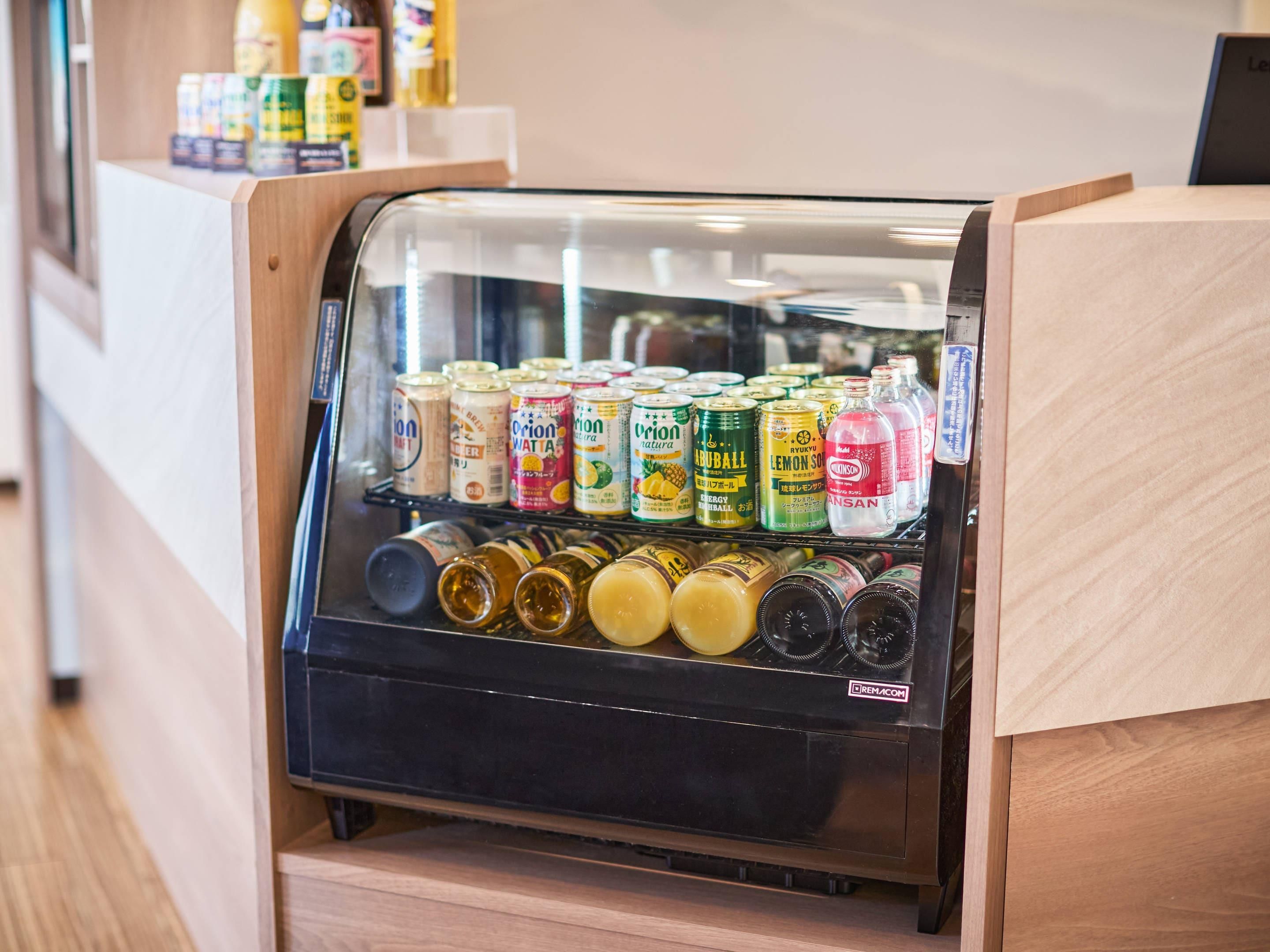 A refrigerated display case with various beverages, including cans and bottles, in a store setting.