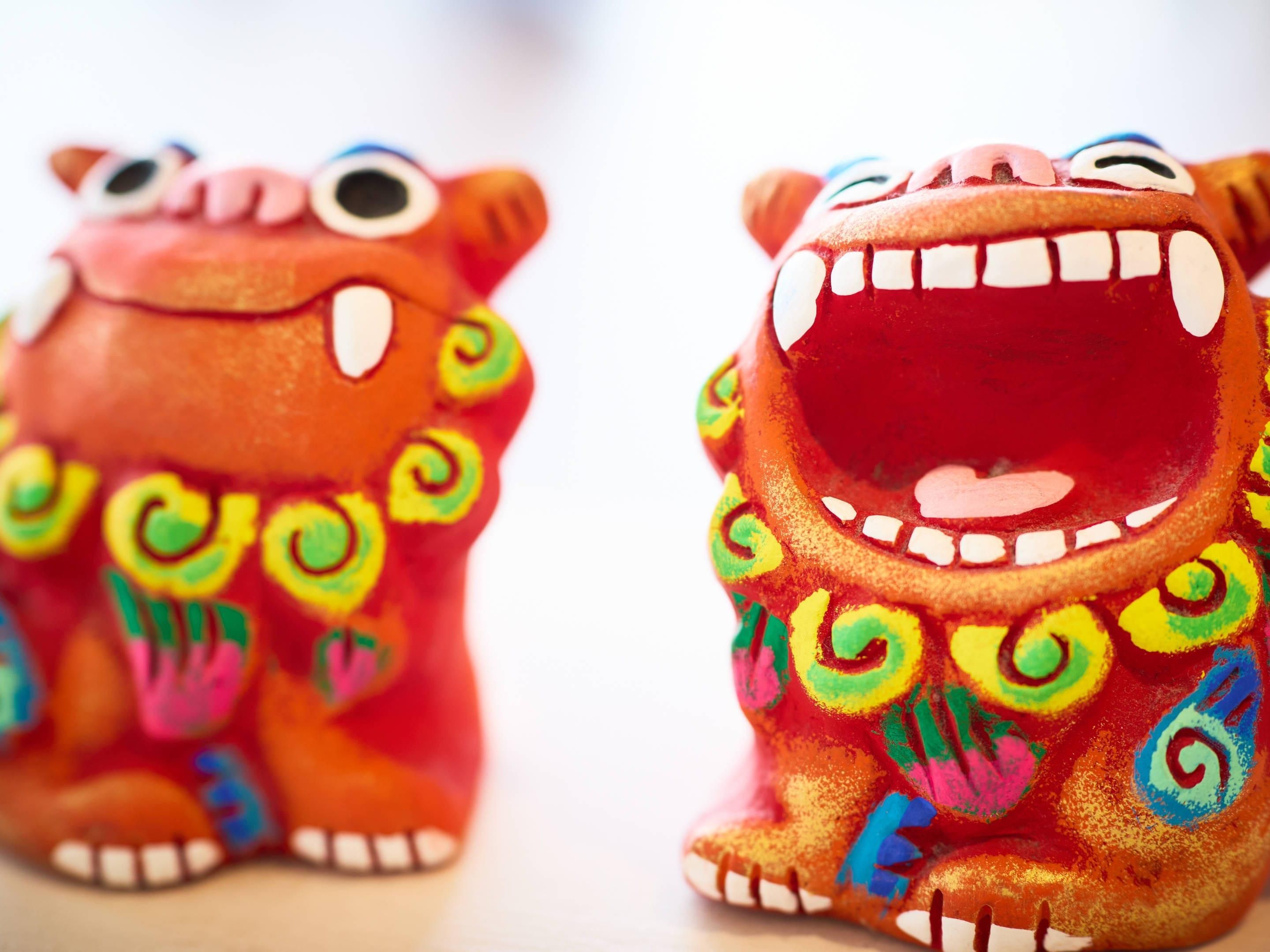 Dues figurines d'animals de ceràmica amb trets facials exagerats i dibuixos de colors.