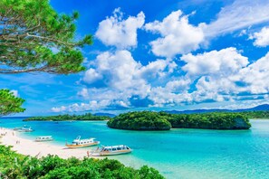 A tropical beach with clear turquoise waters, boats, and lush greenery. - Comfort Hotel ERA Ishigaki Island (Ishigaki)