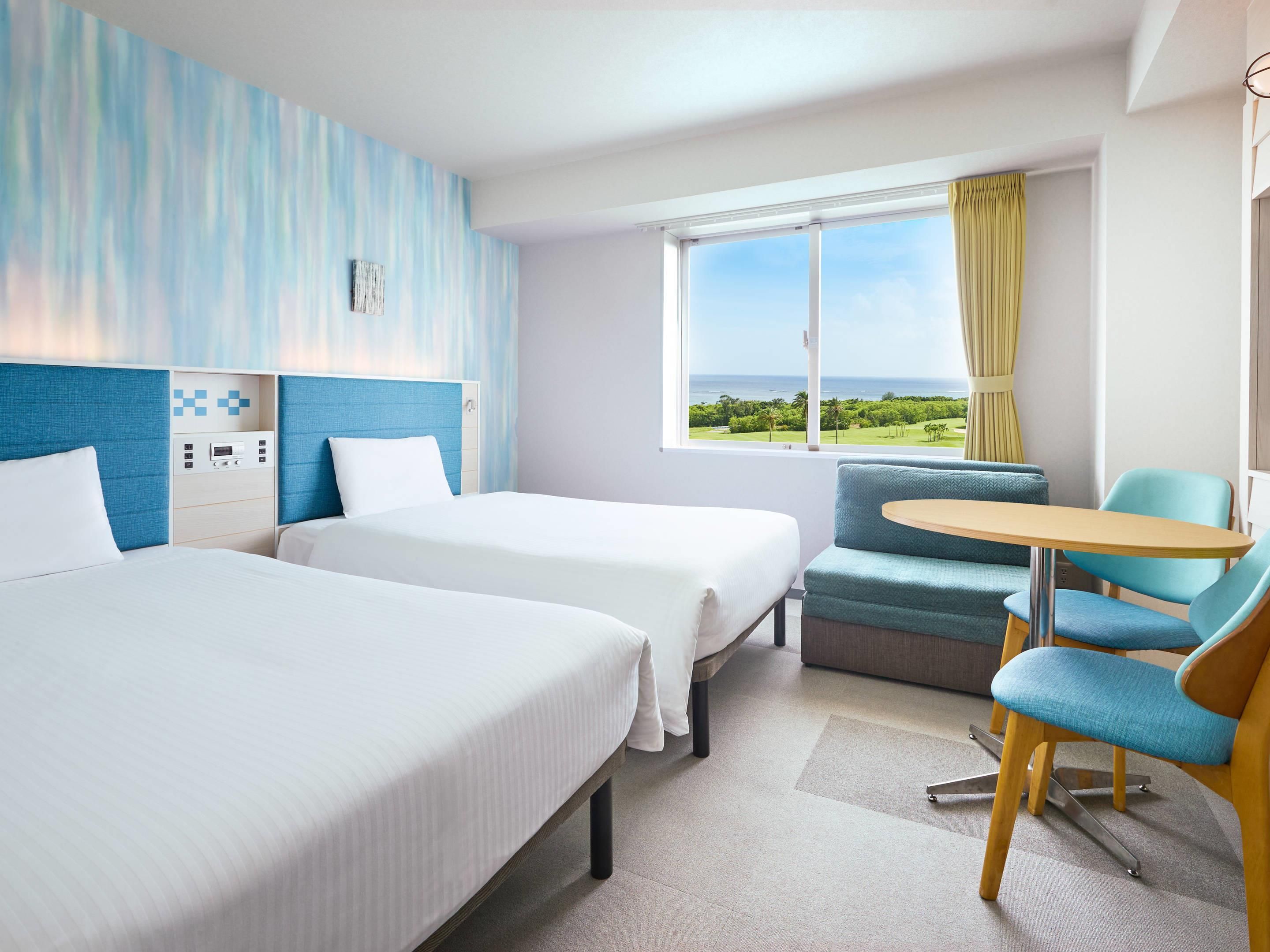 Une chambre d’hôtel avec deux lits, une petite table et une chaise. Il y a une fenêtre donnant sur l’extérieur.