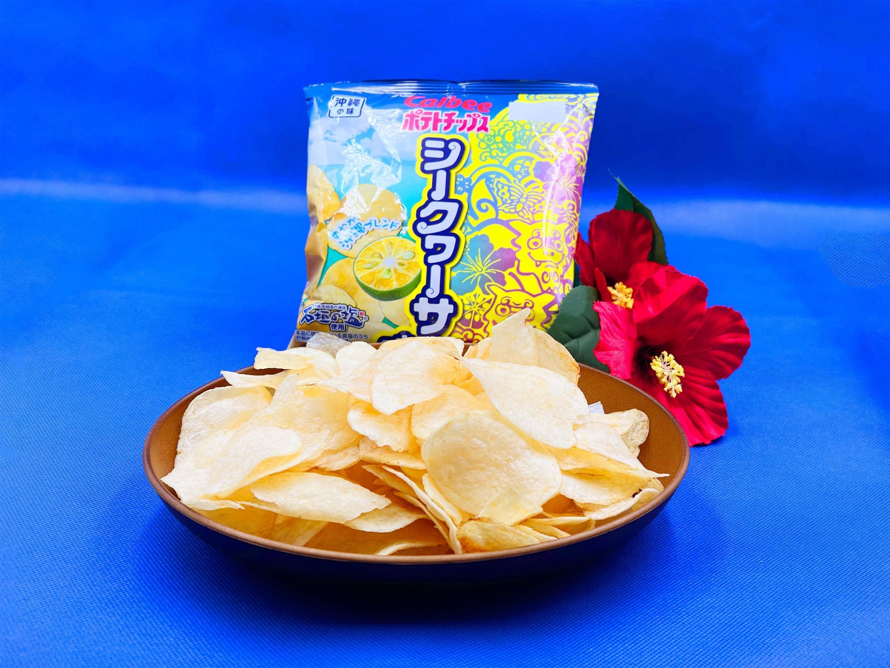 Un tazón de papas fritas y una lata de papas Calbee con sabor a limón sobre una superficie azul.