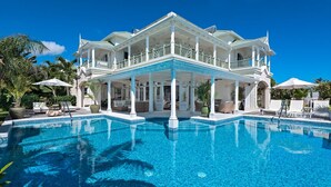 Une grande maison à deux étages avec une piscine à l’avant.