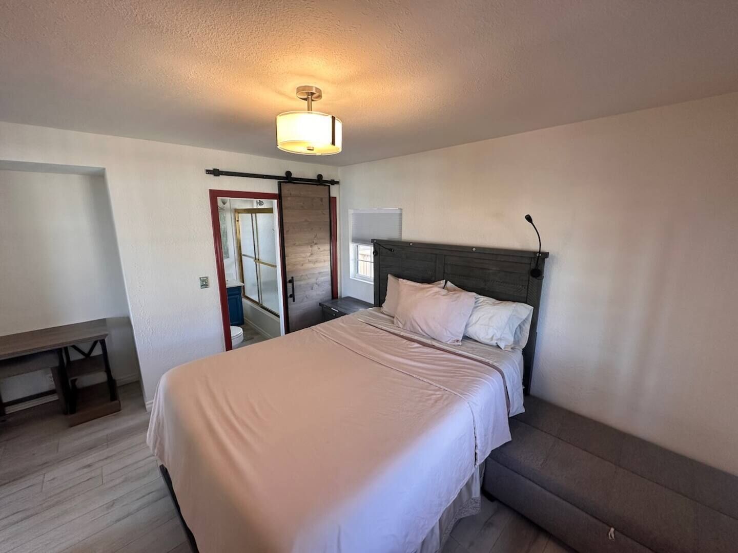 A bedroom with a bed, a bench, a wardrobe, and a ceiling light.