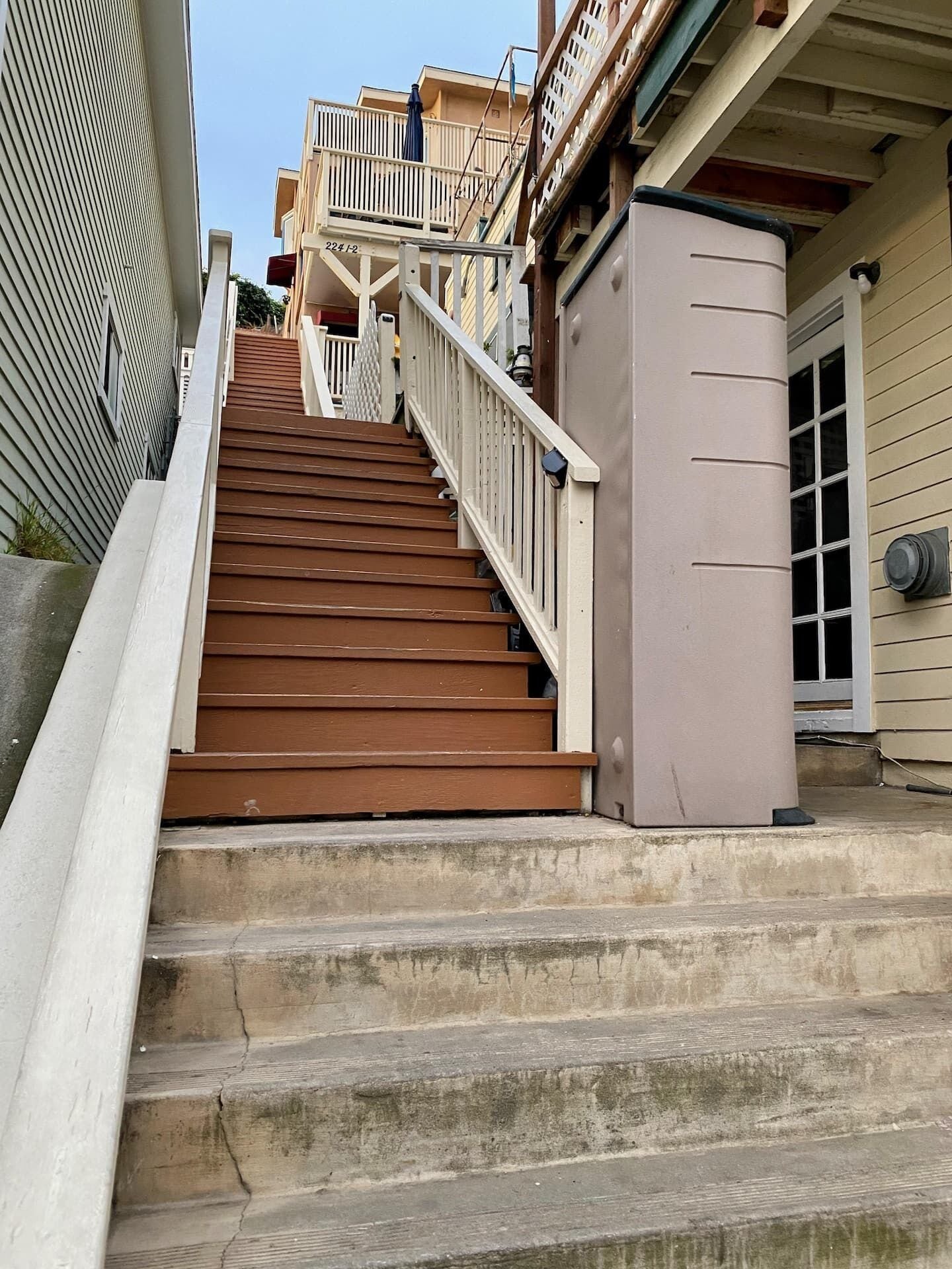 A set of wooden stairs leading to a balcony with a railing.
