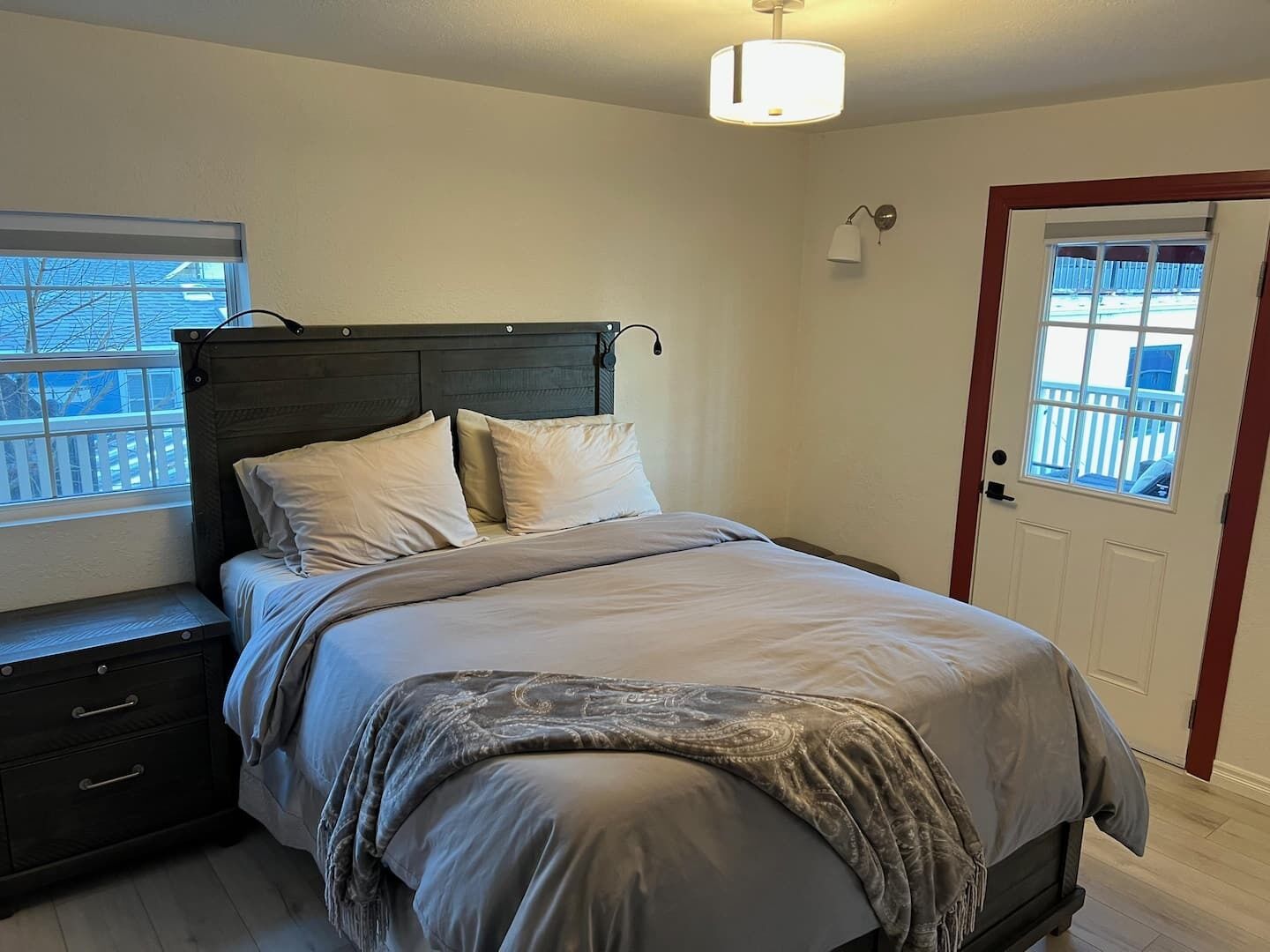 A bedroom with a bed, bedside tables, a window, and a door.