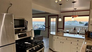 A modern kitchen with a stainless steel refrigerator, a built-in oven, a microwave, and a gas stove. There is a large island with a sink and a view of the ocean through the windows. - Catalina Two Bedroom, Two Bath  View Home (Avalon)