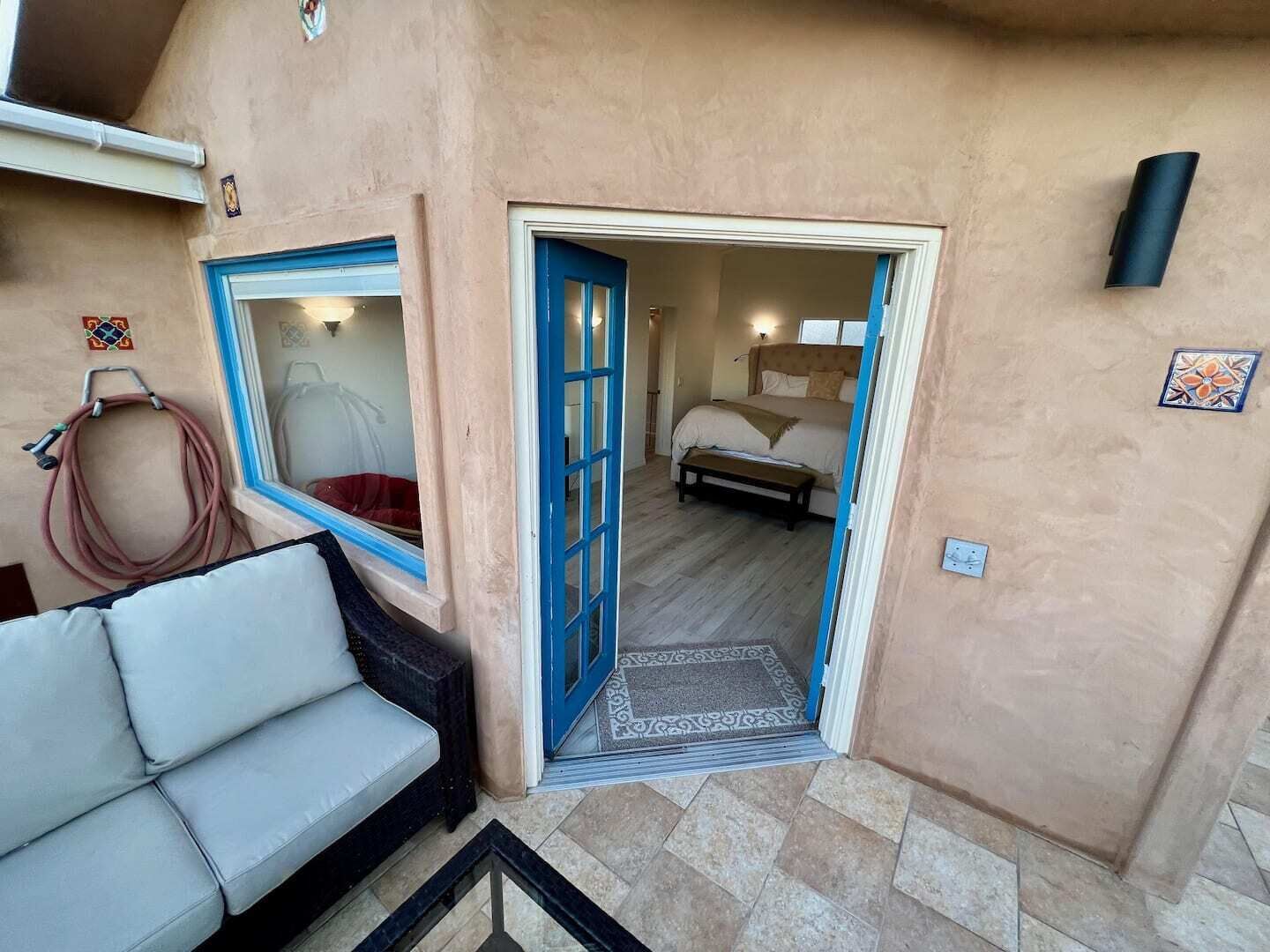 A bedroom with a bed, a window, and a door leading to another room.