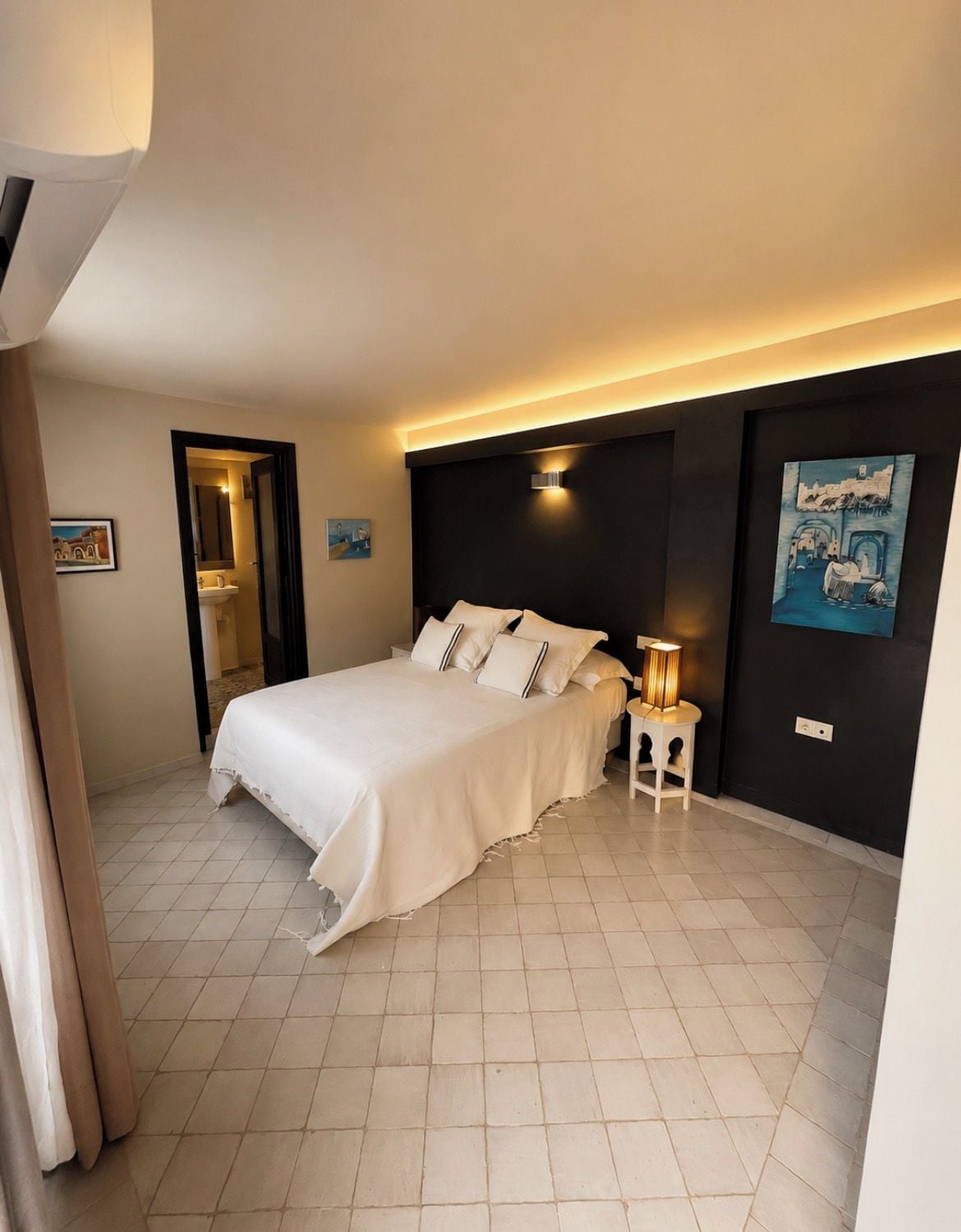 A hotel room with a bed, bedside table, and artwork on the wall.