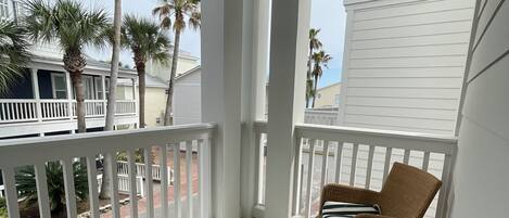 A covered porch with wicker furniture and a view of the beach.