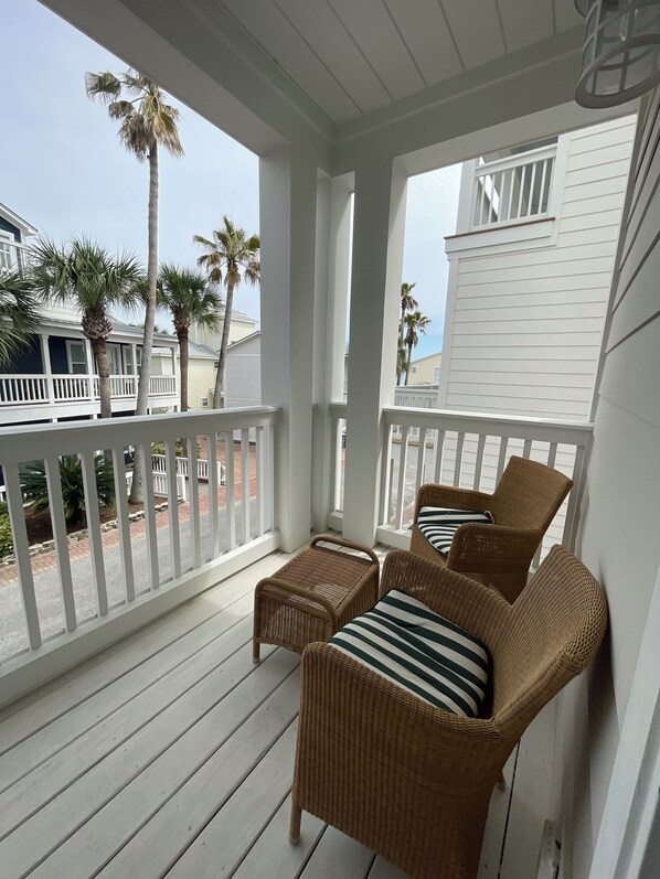 A covered porch with wicker furniture and a view of the beach.