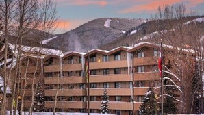 A multi-story hotel with balconies, surrounded by snow-covered trees and a mountainous backdrop. - Scorpio Condos with Great Vail Mountain Views by RedAwning (Vail)