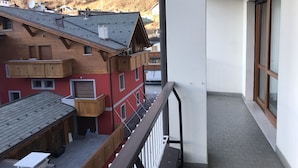 Ein Balkon mit Blick auf umliegende Gebäude und eine hügelige Landschaft.