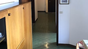 Ein Flur mit Holzausstattung, einem grün gemusterten Boden und gerahmten Bildern an der Wand.